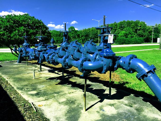 Bank of blue backflow preventers and gate valves on a concrete pad serving a commercial property