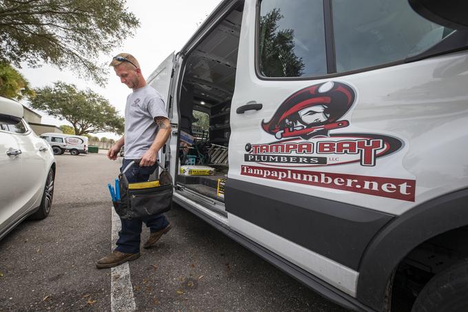 Tampa Bay Plumbers technician carrying a tool bag from a branded company van