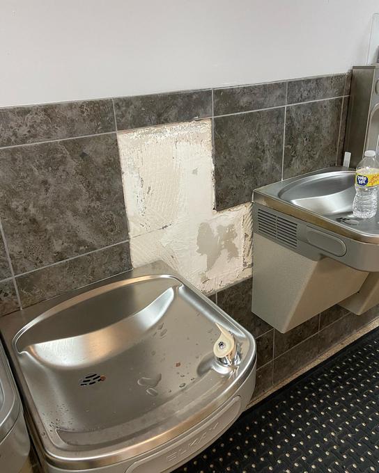 Old drinking fountain still in place beside a patched wall where the second unit was removed