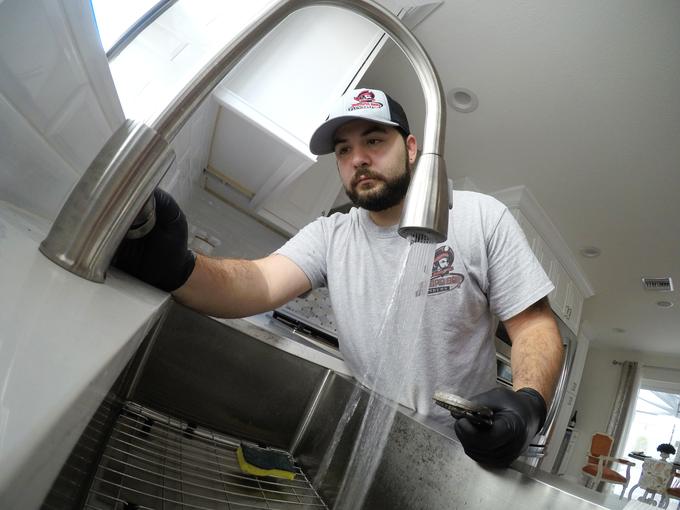 Tampa Bay Plumbers technician testing a pull down kitchen faucet with the water running