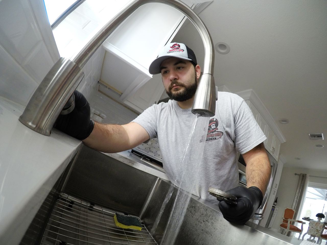 Tampa Bay Plumbers technician testing a pull down kitchen faucet with the water running