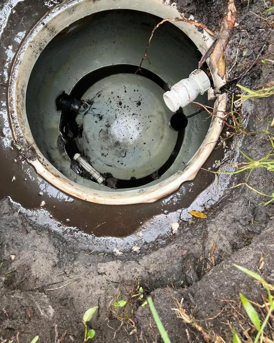 Looking down into a septic pump tank at the float switches and PVC discharge fitting