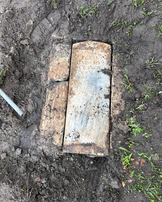 Old in-ground tank lid uncovered in a muddy excavation before the tank is opened