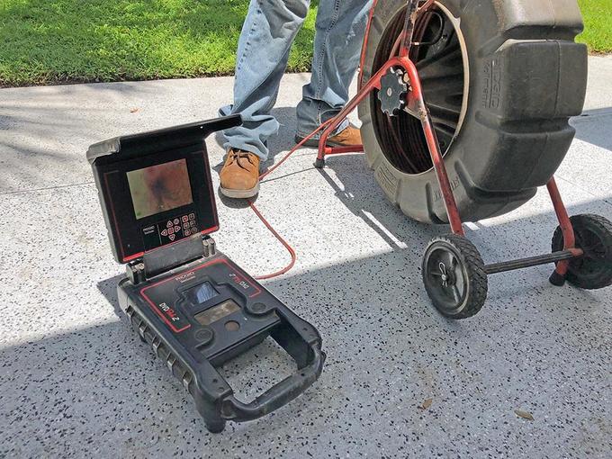 Sewer camera monitor and drain cable reel set up on a driveway outside a Tampa home