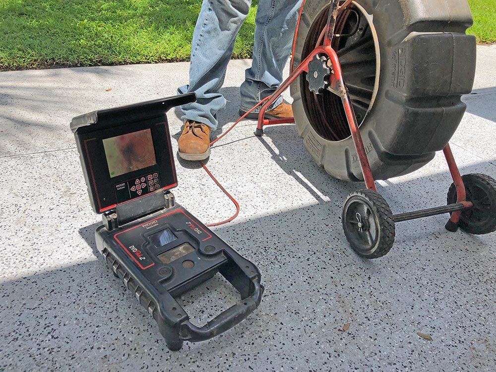 Sewer camera monitor and drain cable reel set up on a driveway outside a Tampa home