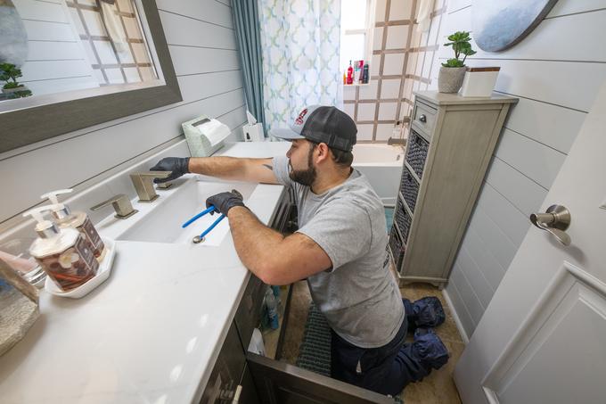 Technician working at a bathroom vanity sink and faucet in a Tampa home